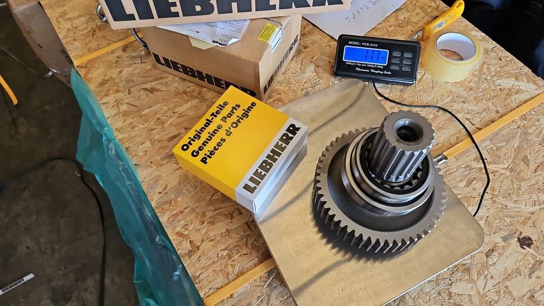Genuine Liebherr gear with bearing and Original-Teile Genuine Parts box on weighing scale